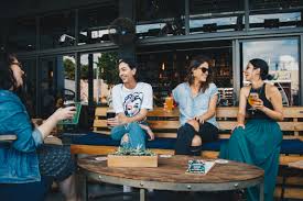 A group of people sit around a table talking and drinking coffee.
