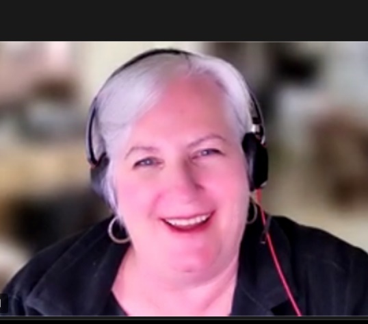 Zelda with a huge smile on her face.  She is wearing headphones, ready for that next Zoom call.