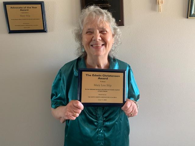 Mary Stip in beautiful green blouse holding her Edwin Christensen Award.