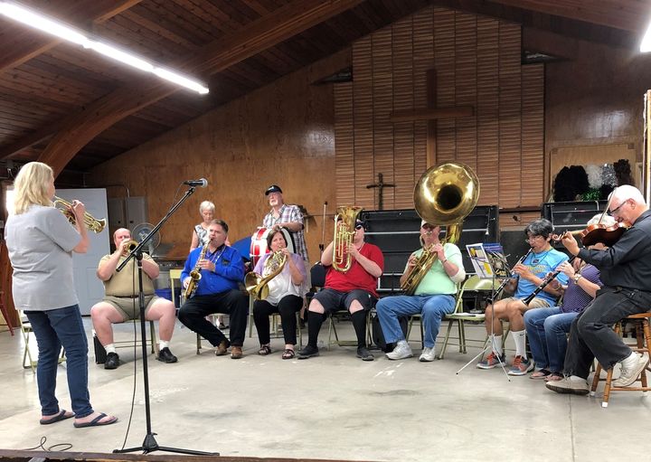 Photo is of the Camp band, everyone gathered around with Lexee leading the group with her trumpet.